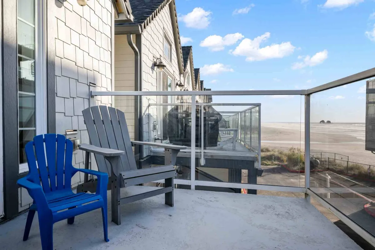 This exterior image features a cozy outdoor seating area with blue and gray chairs, glass railing, and a distant landscape, inviting guests to enjoy conversations and relaxation while soaking in the scenery.