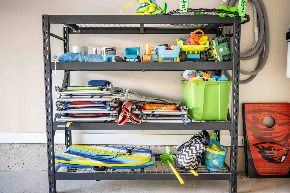 A playful and functional storage space is captured here, with a metal shelving unit holding colorful toys, beach gear, towels, and a green storage bin. The environment looks ready for families to grab what they need for the beach or outdoor adventures.